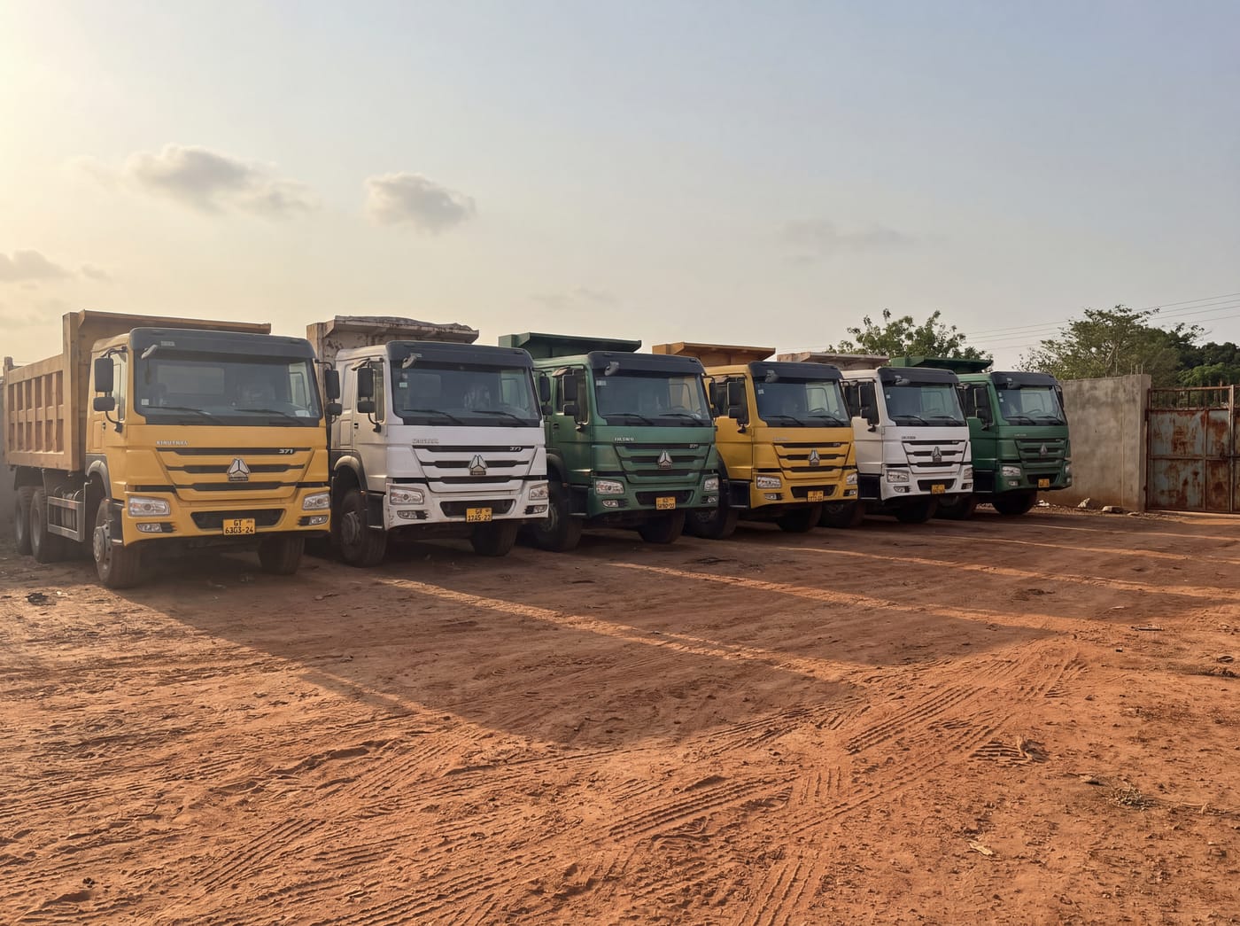 Elim Transport trucks lined up in the yard, gate and signage in frame